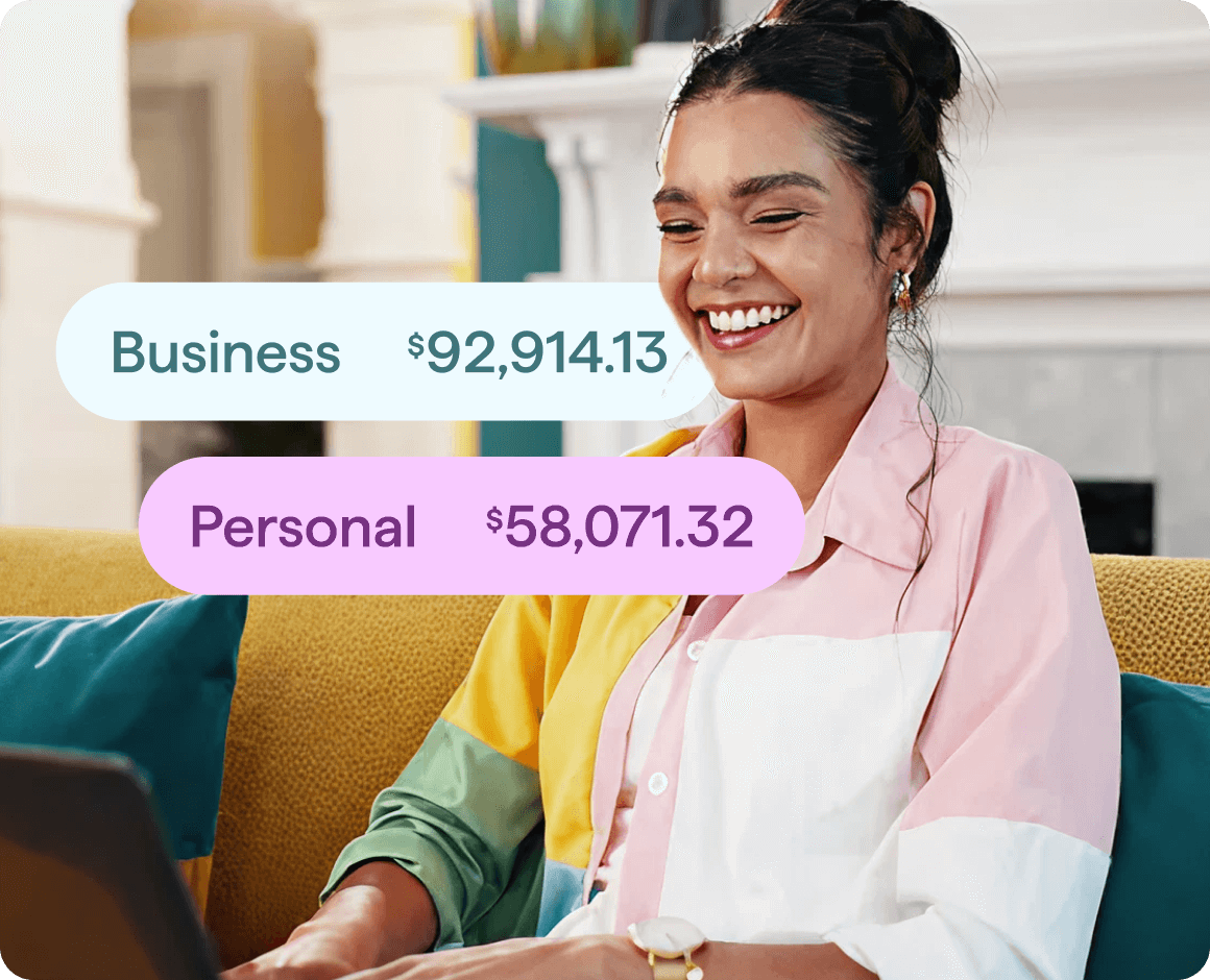 A person sits on a couch using a laptop and smiling. Overlaid on the image are two rounded labels showing account balances: one labeled ‘Business’ with $92,914.13 and another labeled ‘Personal’ with $58,071.32.
